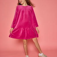 Model can be seen wearing a long sleeve magenta velour dress. Dress features button closure at back for a relaxed but secure fit.