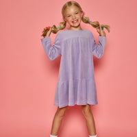 Model can be seen wearing a long sleeve lilac velour dress. Dress features button closure at back for a relaxed but secure fit.