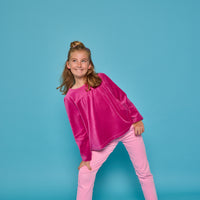 Model can be seen wearing long sleeve velour magenta top paired back with a pair of bubblegum pink corduroy pants. Top features button closure at back ad pants have pockets as well.