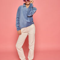Model can be seen wearing a dusty blue velour pullover that features a fold over collar for easy over the head access. Paired back with basic white denim jeans to complete the look.