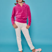 Model can be seen wearing a magenta velour pullover that features a fold over collar for easy over the head access. Paired back with basic white denim jeans to complete the look.