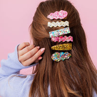Person with colorful hair clips against a pink background