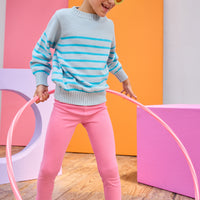 Tween model can be seen wearing an aqua stripe sweater paired back with leggings in a hot pink color to complete the vibrant look.