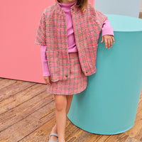 Model can be seen wearing tweed skort in magenta/pink/green plaid pattern paired back perfectly with the cape in the matching print and material.