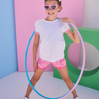 Tween model can be seen wearing a pair of woven hot pink/light pink floral print shorts that feature a ric rac hot pink detail along hem of shorts and an elastic waistband for a comfy but secure fit. Model can also be seen wearing a white tee with the same color light pink/hot pink ric rac detail at bottom of sleeves to complete the look.