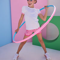 Model can be seen wearing white knit top that features hot pink/light pink ric rac detail at edge of sleeves to elevate the look. Top pairs back perfectly with woven hot pink/light pink ric rac shorts to complete the look.