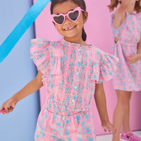 Model can be seen wearing a woven pink and blue floral top that features button closures along the front and big angel sleeve detail to elevate the look. Top pairs back perfectly with the shirred shorts in the same matching print to complete the look.