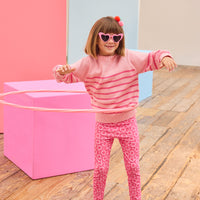 Tween model seen wearing a striped light pink and hot pink sweater paired back with leggings in a fun fall print.