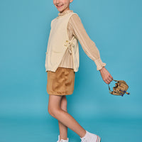 Model can be seen wearing tan/cream pattern woven top paired underneath a cream sweater vest with ties at sides for an elevated look. Paired back with our skort in brown faux suede to complete the look.