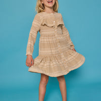 Model can be seen wearing long sleeve woven khaki gingham dress. Dress features buttons down the front and a ruffle at the bodice for an elevated look.