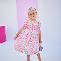 Girls/tween woven dress in a lavender/salmon floral print with matching lavender piping across bust and sleeves. Dress features button closures along back and made of a lightweight material that is lined for a secure but comfy fit.