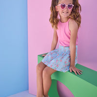 Tween model can be seen wearing a smocked waist woven skirt in a pink and blue floral print. Skirt features smocking detail at waist for a secure but comfy fit. Skirt pairs back perfectly with a hot pink halter top that has button closures along back.