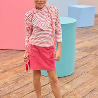 Model can be seen wearing velour skort in a beautiful pink shade that features an elastic waistband, built in shorts, and pockets in the front for an elevated look. Pair the skort back with a long sleeve knit top with a v-detail ruffle in pink and white stripe to complete the look.