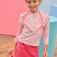 Model can be seen wearing velour skort in a beautiful pink shade that features an elastic waistband, built in shorts, and pockets in the front for an elevated look. Pair the skort back with a long sleeve knit top with a v-detail ruffle in pink and white stripe to complete the look.