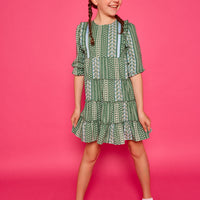 Model can be seen wearing woven dress in a green/blue/white floral. Dress features four tier detail to elevate the dress.