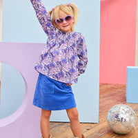 Model can be seen wearing a royal blue velour skort that features an elastic waistband, built in shorts, and two functioning pockets in the front of skort. Pair skort back with purple/blue/white floral top to complete the look.