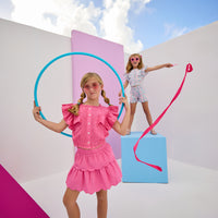 Model can be seen wearing woven hot pink two tiered skort. Skort features elastic waistband and built in shorts for a secure fit. Skort pairs back perfectly with woven hot pink top in same fabric to complete the look.