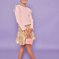 Model can be seen wearing a bubblegum pink ribbed knit long sleeve t-shirt with tulle sparkle star fabric at top of sleeves for elevated look. Paired back with a gold skort in a metallic lurex material that has built in shorts for a secure fit.