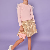 Model can be seen wearing a bubblegum pink ribbed knit long sleeve t-shirt with tulle sparkle star fabric at top of sleeves for elevated look.Paired back with a gold skort in a metallic lurex material that has built in shorts for a secure fit.
