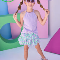 Model can be seen wearing a lavender halter tank top that features button closure along back and is made of a stretchy knit fabric. Top pairs back perfectly with tiered skort in the purple/aqua/green floral to complete the look.