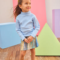 Model can be seen wearing a multi stripe wool skort in a brown/blue/aqua pattern paired back with a ribbed turtleneck in light blue to complete the look.