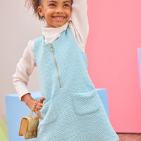 Model can be seen wearing a knit quilted jumper in an aqua color that features a gold quarter zip zipper and two functional pockets in the front for an elevated look. Pair a ribbed turtleneck underneath to complete the look.