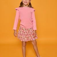 Model can be seen wearing a long sleeve pink and white stripe knit t-shirt that features ruffles at the sleeves. Paired back with our skort in a red/pink/yellow floral print, that has built in shorts, to complete the look.