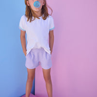 Model can be seen wearing a white knit tee that has a aqua/lavender ric rac detail at cuffs of sleeves. Shirt pairs back perfectly with knit lavender shorts to complete the look.
