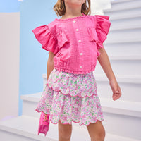 Model can be seen wearing a two tiered skort in a light pink/hot pink/and green floral print. Skort features build in shorts, an elastic waistband, and hot pink embroidered scallop edges for an elevated look. Skort pairs back perfectly with hot pink woven short sleeve angel sleeve top that features buttons down the front for a secure but comfy fit.