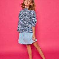 Model can be seen wearing a woven top with a ruffle neckline and button closure along back. The purple/teal/blue floral print pairs back perfectly with our skort in light blue corduroy to complete the look.