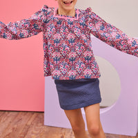 Model can be seen wearing a navy quilted knit skort that features an elastic waistband and built in shorts for a relaxed but secure fit. Skort pairs back perfectly with long sleeve woven top in navy/pink/cranberry floral print to complete the look.