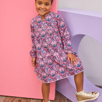 Model can be seen wearing long sleeve woven dress in a beautiful navy/pink/cranberry floral print. Dress features a beautiful light pink ric rac detail along neckline and bottom tier of dress and also features button closure along back for easy put on access.