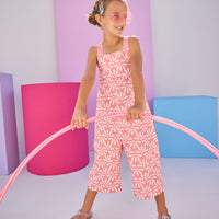 Girls/Tween model can be seen in knit jumpsuit in a salmon/pink and white floral print.This jumpsuit has adjustable woven straps and pockets for easy relaxed fit.
