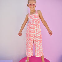 Girls/Tween model can be seen in knit jumpsuit in a salmon/pink and white floral print.This jumpsuit has adjustable woven straps and pockets for easy relaxed fit.