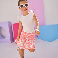 Girls/Tween model can be seen wearing a knit eyelet angel sleeve tank that pairs back perfectly with this skort in a salmon and white floral pattern.