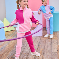 Model can be seen wearing a matching color block set in pink/cranberry/and white. Pullover features a gold quarter zip zipper detail and large front pocket for a relaxed but secure fit. Pullover matches back perfectly to the joggers, and continues with the color block with a pink pant leg and an cranberry pant leg.