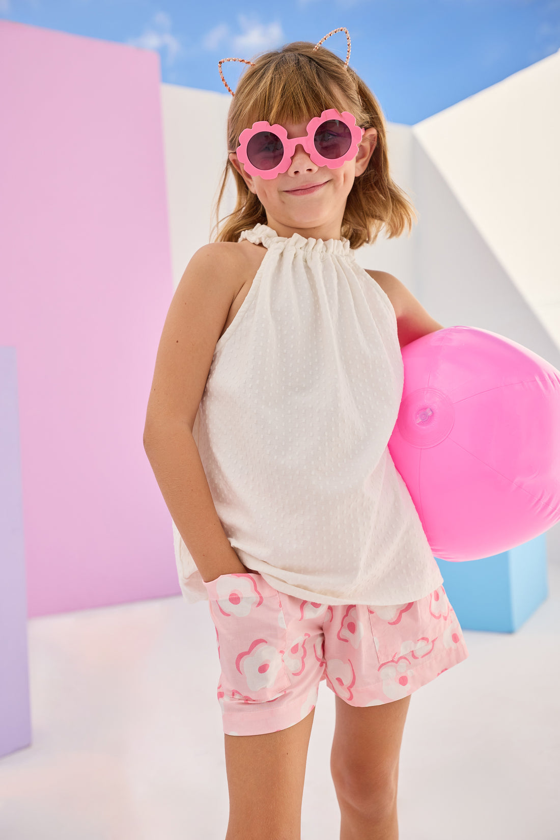 Girls/Tween woven shorts in a light pink and white floral print. Shorts have an elastic waistband and pockets in the front for a comfy and secure fit. Model can be seen pairing these shorts with our sleeveless tank top in a gorgeous white pointelle fabric.