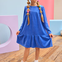 Model can be seen wearing a long sleeve royal blue velour dress which is made of a soft and stretchy velour and also features ruching along top tier and bottom tier of dress for an elevated look.