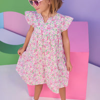 Model can be seen wearing a woven dress in a pink/green floral print. Dress features a slight v-neckline, angel sleeves, and button closure along back for a secure but comfy fit.