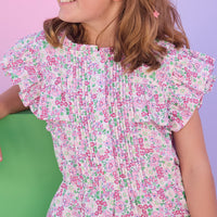 Young girl in a floral dress with pink sunglasses and a pink clutch against a colorful background