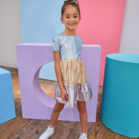 Tween model can be seen wearing a metallic dress that has an ice blue metallic top, gold metallic waist, and purple metallic bottom tier for a fun elevated look.