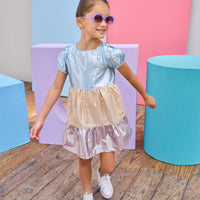 Tween model can be seen wearing a metallic dress that has an ice blue metallic top, gold metallic waist, and purple metallic bottom tier for a fun elevated look.