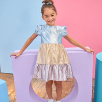 Tween model can be seen wearing a metallic dress that has an ice blue metallic top, gold metallic waist, and purple metallic bottom tier for a fun elevated look.