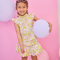 Model can be seen wearing woven two tiered skort in a pink/yellow floral print. Skort features built in shorts, elastic waistband, and a cream scallop embroidery detailing to complete the look. Skort pairs back perfectly with woven top in the same print to complete the look.