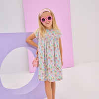 Girls/tween woven dress in a pale yellow/pink/blue/green floral pattern. Dress is made of a lightweight woven material, is lined, and has a 3 button closure along back for a secured but relaxed fit.