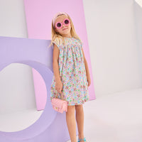 Girls/tween woven dress in a pale yellow/pink/blue/green floral pattern. Dress is made of a lightweight woven material, is lined, and has a 3 button closure along back for a secured but relaxed fit.
