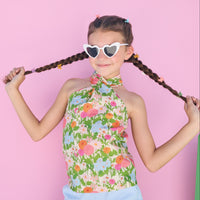 tween girl in a floral top and light blue shorts posing against a colorful background