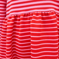 Model can be seen wearing a thick knit long sleeve dress that features a square neckline, elastic cuffs at sleeve, and a mix and match pink and red stripe detail to elevate the look.