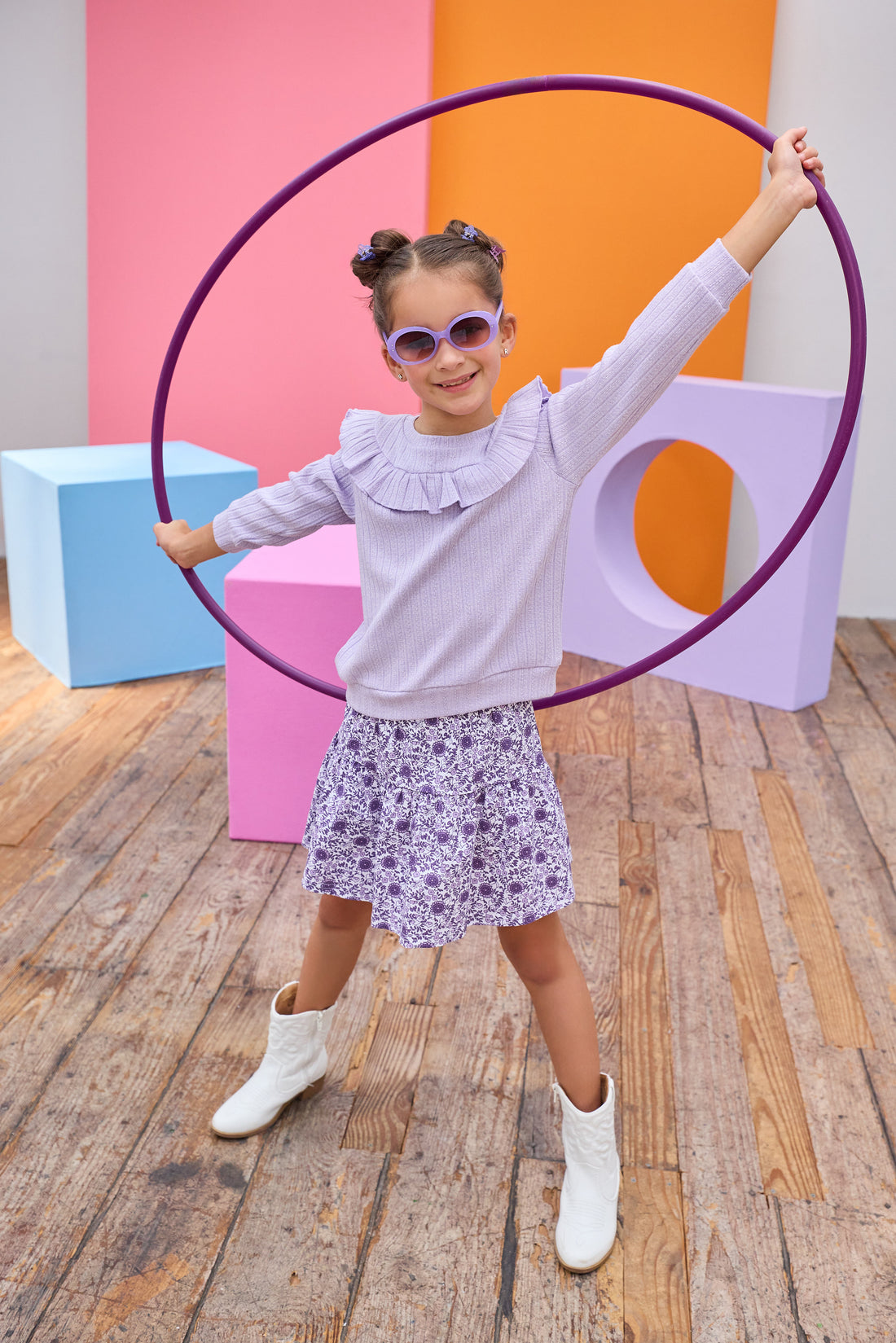 Model can be seen wearing a knit skort in a beautiful purple floral print. Skort features an elastic waistband and built in shorts for a relaxed but secure fit. Top pairs back perfectly with cable knit purple long sleeve top with ruffle detail across bust/top of sleeves to complete the look.