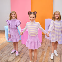 Tween girl in the middle seen wearing a lavender corduroy skirt paired back perfectly with our soft turtleneck in a lavender and cream stripe. Girls on the left and right can be seen wearing similar styles, in the same fabric, for a perfect mix and match.